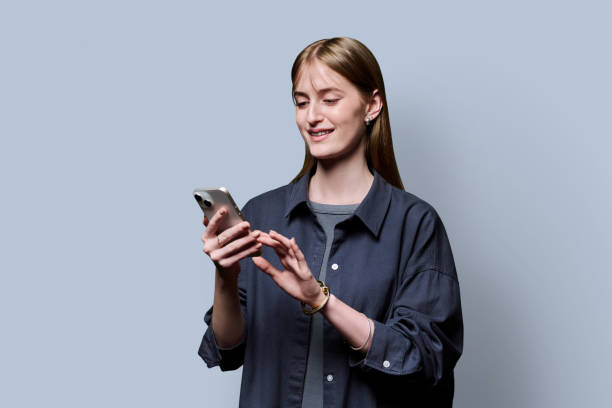 istock Young beautiful woman using smartphone on grey studio background 2182841717