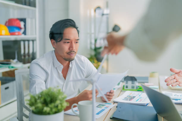 istock A focused man reviews documents in modern office, surrounded by design materials and small wind turbine model, reflecting commitment to sustainable energy solutions 2182849753