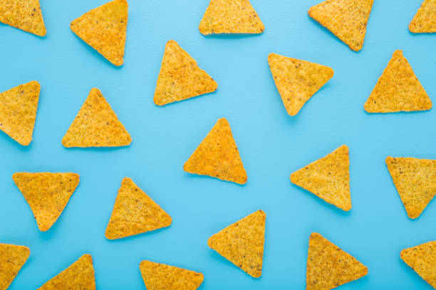 istock Yellow tortilla chips on light blue table background. Pastel color. Snack pattern. Closeup. Top down view. 2182849942