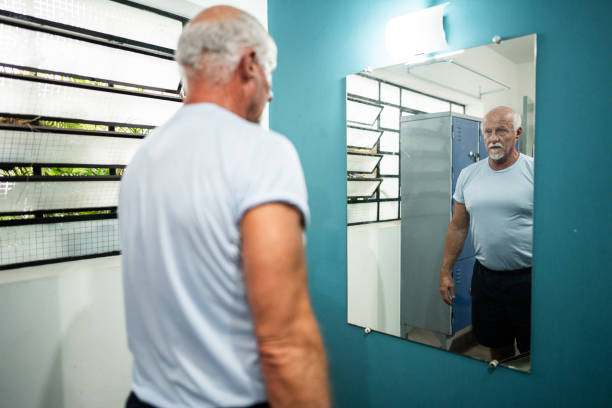 istock Senior man looking in mirror in a locker room 2182850905