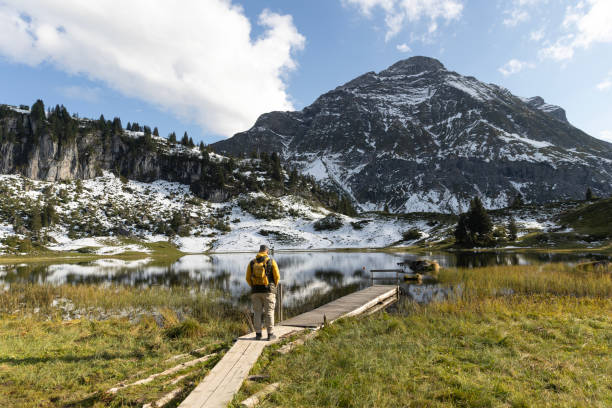 Handsome redhead senior man enjoying a moment of downtime at a lake during a forest bathing meditation trip in the Austrian Alps