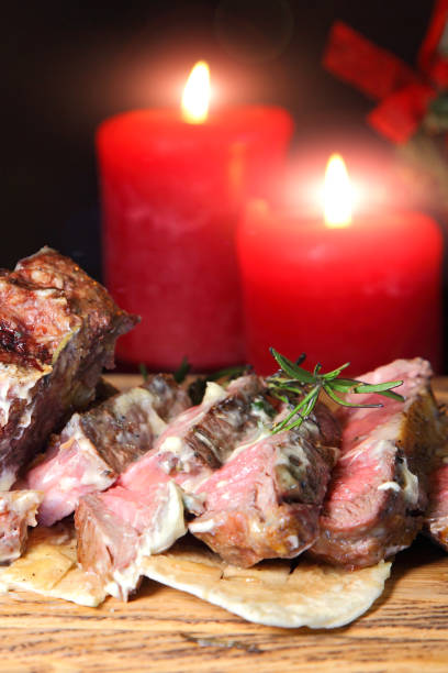 Christmas steak by candlelight. Christmas atmosphere and the mood to eat delicious steaks. Beef steak on a wooden board. Christmas table and steak.