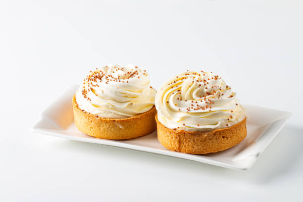 istock Lemon tartlets with whipped cream, sprinkles and chocolate chips on white background 2182853331