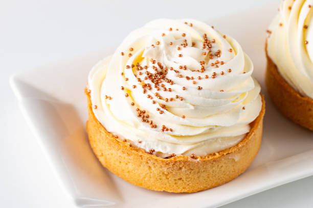 Lemon tartlets with whipped cream, sprinkles and chocolate chips on white background