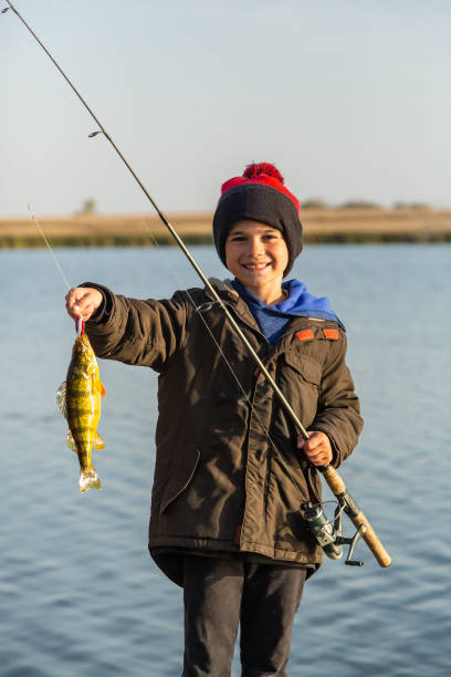 istock Boy Holding Up Perch He Just Caught While Fishing 2182856356