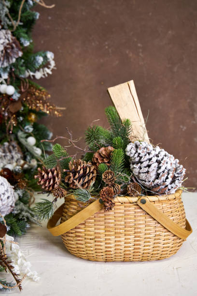 istock Christmas decor, wicker basket with pine branches, cones and firewood on a dark background 2182858625