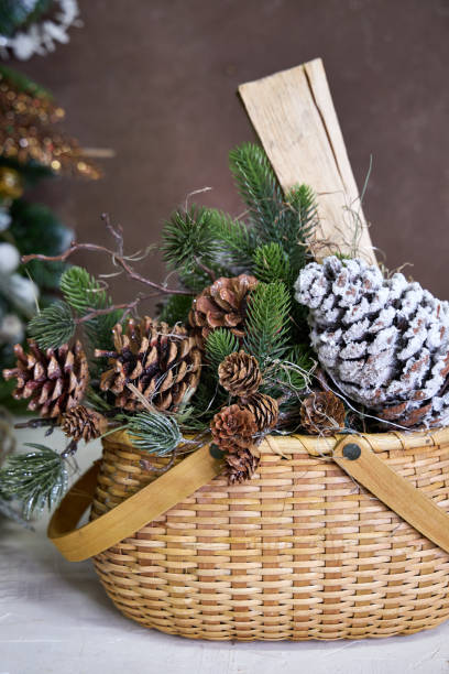istock Christmas decor, wicker basket with pine branches, cones and firewood on a dark background 2182858630