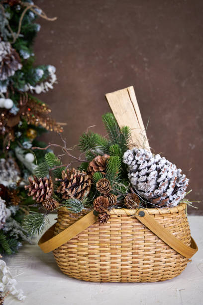 istock Christmas decor, wicker basket with pine branches, cones and firewood on a dark background 2182859057