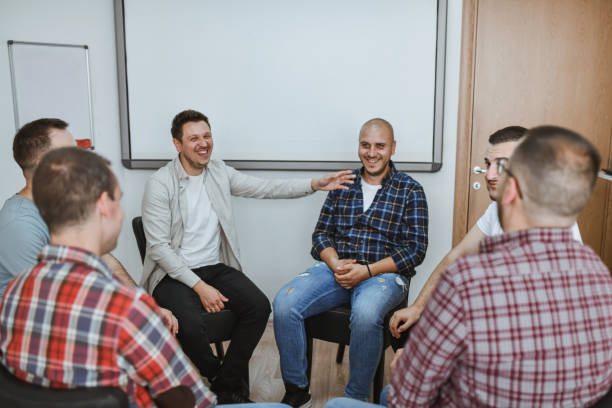 istock Group of Male Adults Sitting in Circle in Support Group Telling Funny Stories 2182862607