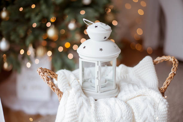Christmas decor. Flashlight with a candle, knitted sweater, wicker basket against the background of a Christmas tree.