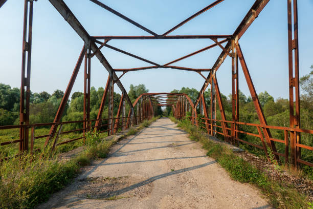 View along abandoned road across old bridge with rusty metal beams construction. Background. Landscape.