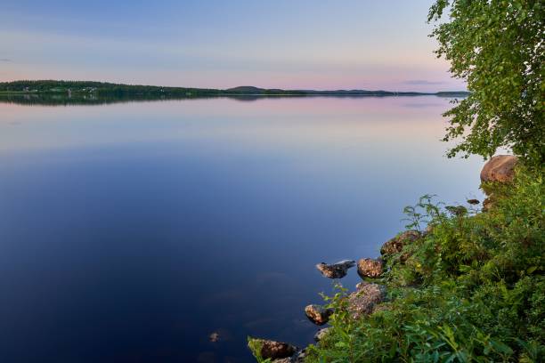 istock Serene lakeside scene at sunset with a pink-blue sky, and greenery on the shore 2182875786