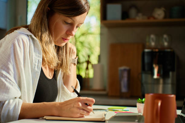 istock Woman working at home, writing in notebook and using laptop 2182879276