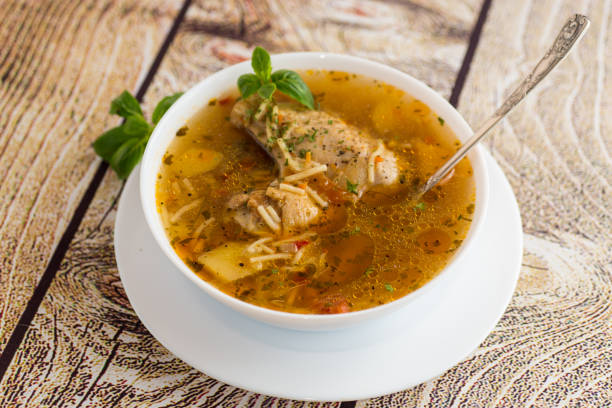 hot cooked chicken and noodle soup in a plate on a wooden table.