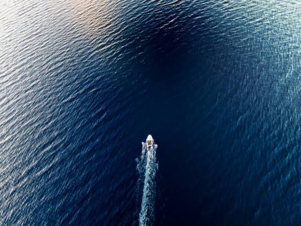 istock Slow small boat along the open sea leaving white trail. High angle view from drone. 2182882256