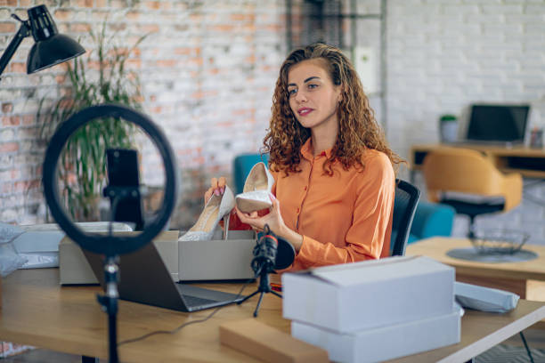 istock Woman fashion designer using live streaming on mobile phone while unpacking products 2182888333