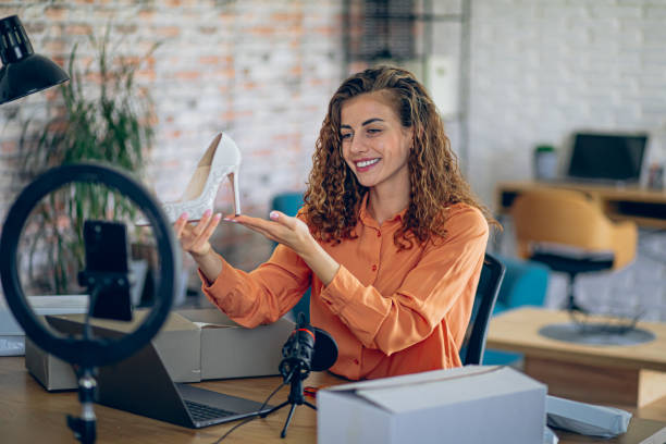 istock Woman fashion designer using live streaming on mobile phone while unpacking products 2182888349
