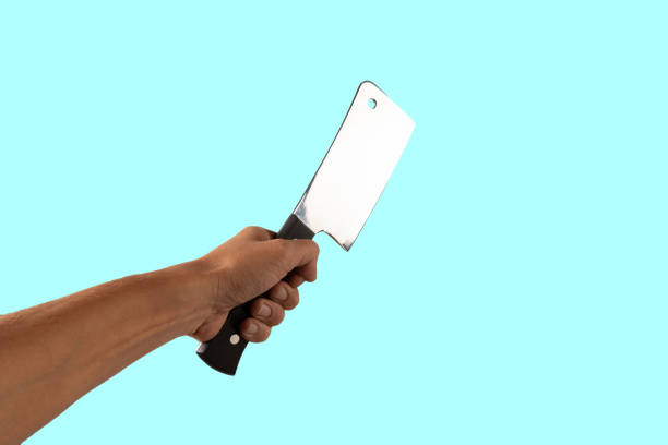Hand holding a butcher knife isolated on cyan background. High quality photo
