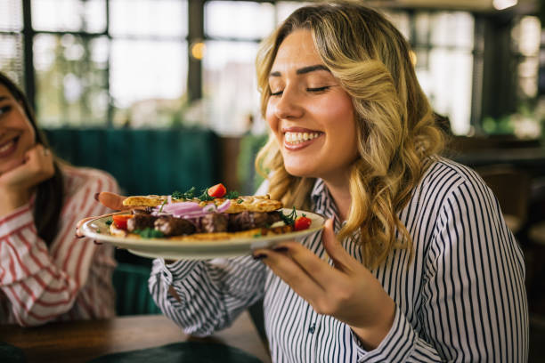 Beautiful blonde woman happy to eat grilled meat in a restaurant. stock photo