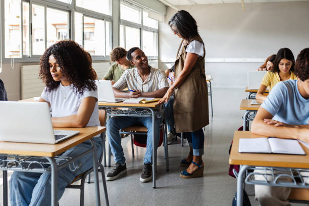 istock Senior female teacher helping high school student doing exercises in classroom 2182898668