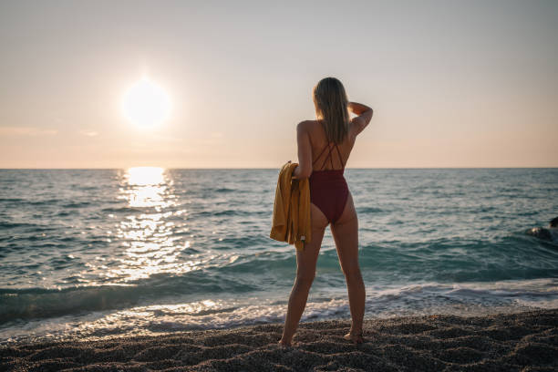 istock Young Woman With a Backpack Looking at the Horizon at the Beach 2182899976