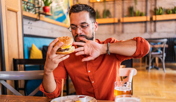 istock Young man eating a delicious burger 2182900075
