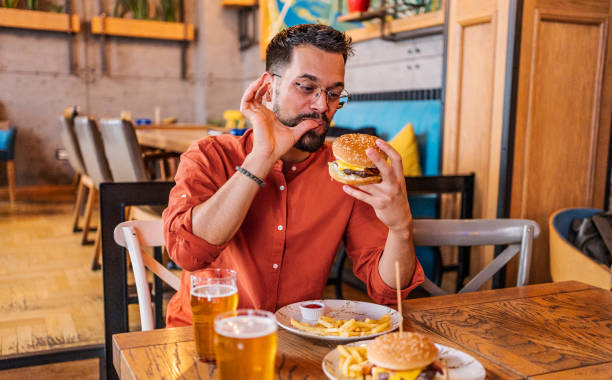 istock Young man eating a delicious burger 2182900215