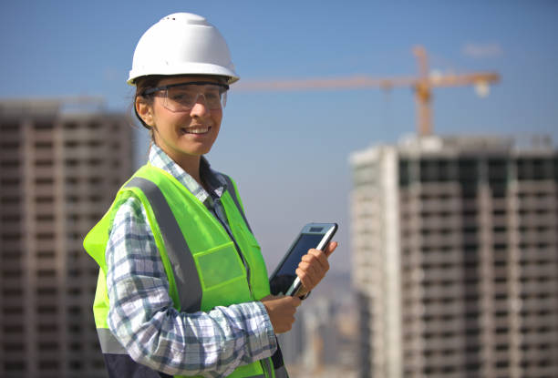 istock Young female civil engineer with a tablet looking at the camera at the construction site. 2182900412