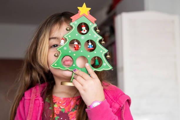 istock A young girl covers her face with a decorated Christmas tree toy. 2182900473