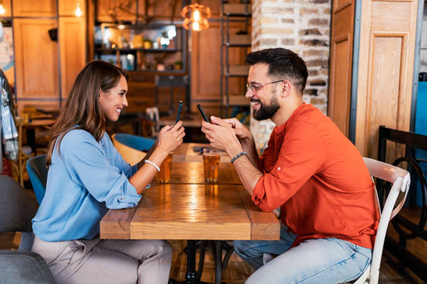 istock Young couple using their smartphones in the pub 2182900615