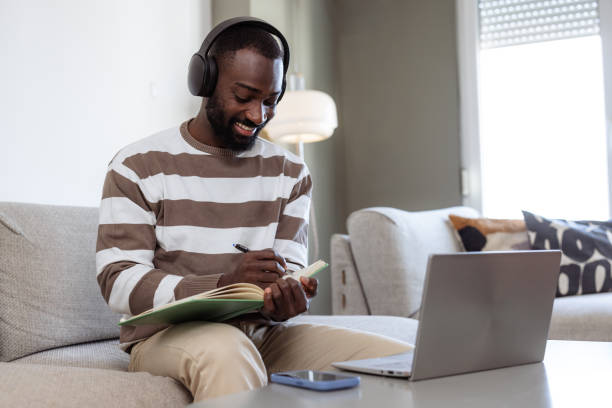 istock African American man writing notes from the course he is listening to online 2182900623