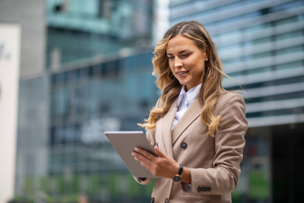 istock Businesswoman using digital tablet in front of office buildings 2182903338