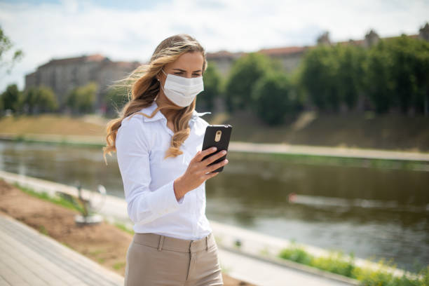 istock Businesswoman wearing face mask using smartphone near river 2182905206