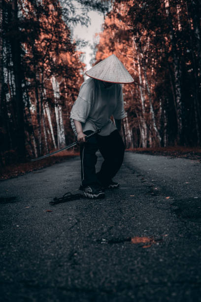 istock A samurai warrior in traditional attire stands with a sharp katana sword on a forest path. The dark, gloomy atmosphere adds to the cinematic quality of the samurai with the katana. 2182905234