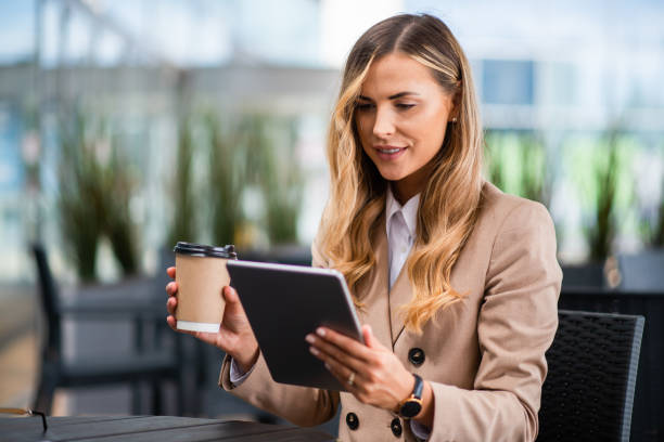 istock Businesswoman using digital tablet and drinking coffee outdoors 2182906758