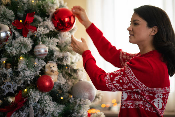 istock A woman puts ornaments on a Christmas tree 2182914134
