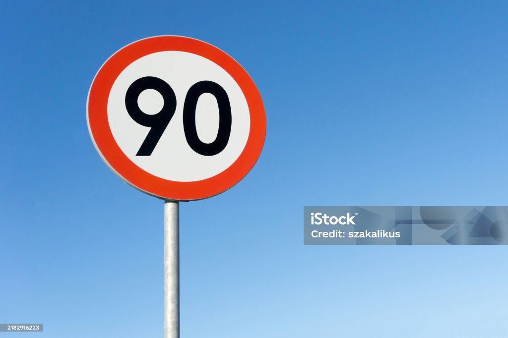 Speed limit sign isolated against a blue sky background. Do not drive fast empty copy space. 90 kmph limit. Road safety ninety kilometers per hour. Maximum allowed speed. Forbidden Stock Photo Speed limit sign isolated against a blue sky background. Do not drive fast empty copy space. 90 kmph limit. Road safety ninety kilometers per hour. Maximum allowed speed. Forbidden Stock Photo