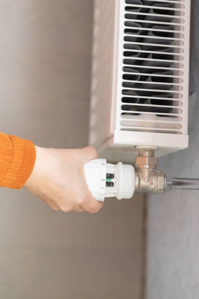 istock a female hand switches the heating radiator 2182917658