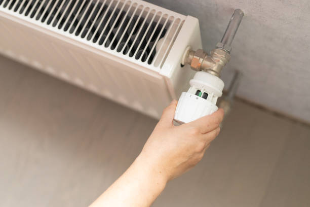 istock a female hand switches the heating radiator 2182917664