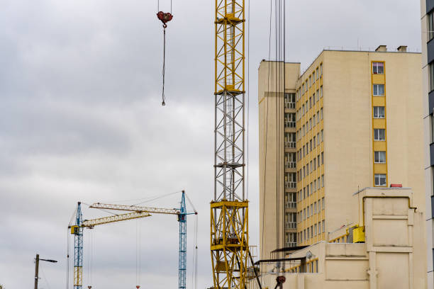 istock Workers actively engage in construction activities surrounded by towering cranes against a backdrop of a gray sky, epitomizing urban development in progress 2182920235