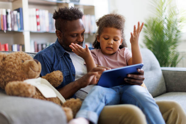 istock Father and daughter are having fun on a tablet at home 2182931580