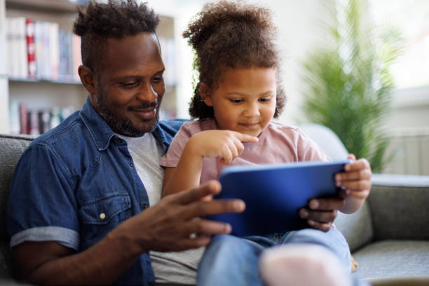 istock Father and daughter are having fun on a tablet at home 2182931587