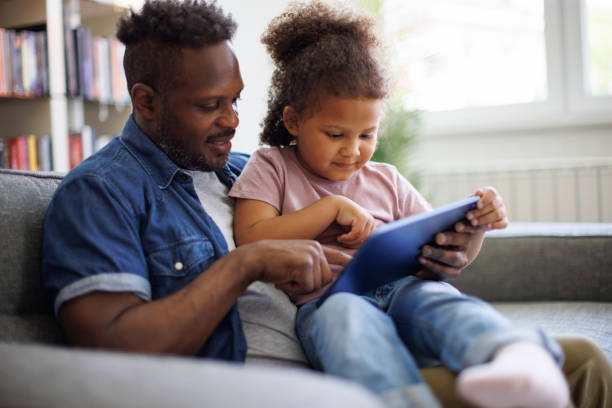istock Father and daughter are having fun on a tablet at home 2182931607
