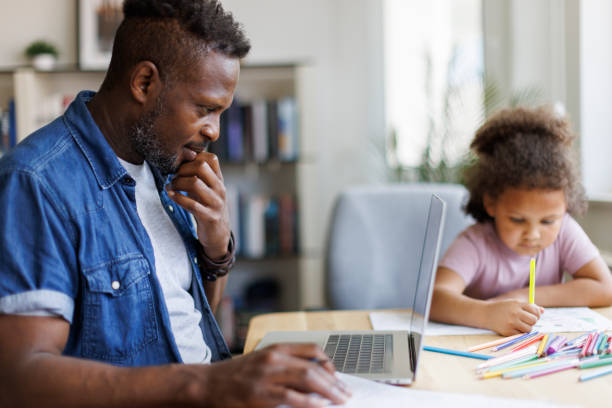 istock Father working on laptop while his daughter doing homework beside him at home 2182931898