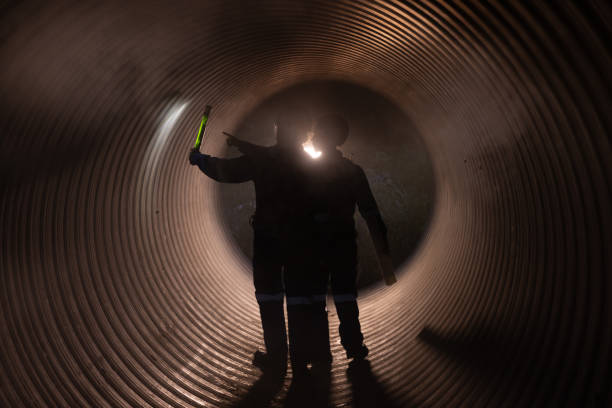 istock Two male construction engineers, with flashlights and safety equipment, inspect the availability of large drainage pipe materials before commissioning the underground system. 2182936001