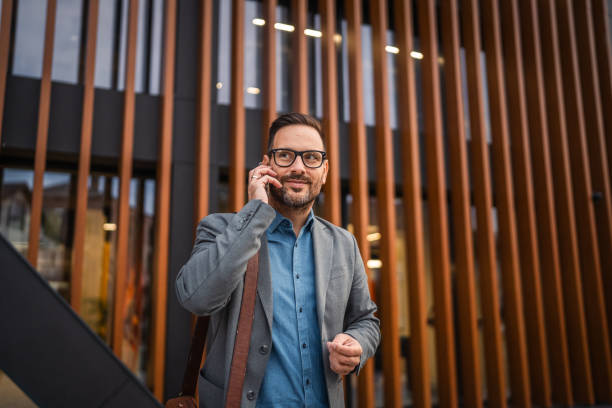 istock satisfied businessman stand in front building and have phone call 2182939430