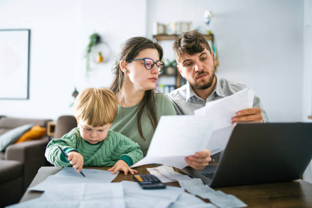 Young family managing budget and paying bills and taxes. Young family of three with a toddler managing their budget,paying bills and taxes online and calculating monthly expenses at home.Inflation concept. critical thinking kids stock pictures, royalty-free photos & images