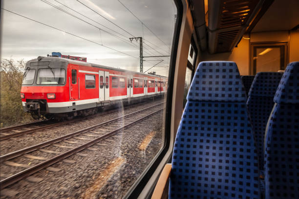 This dynamic photograph features a German suburban train (S-Bahn) traveling near Cologne, as viewed from the window of another passing train. The image conveys a sense of motion and the extensive reach of Germany's public transportation network. The S-Bahn system is integral to urban and regional mobility, providing efficient and reliable service for commuters and travelers. The scene highlights the importance of rail transport in reducing traffic congestion and promoting sustainable travel options. By capturing trains in motion, the photograph emphasizes connectivity, the rhythms of daily life, and the technological sophistication of the country's transportation infrastructure that supports both local and regional transit needs.