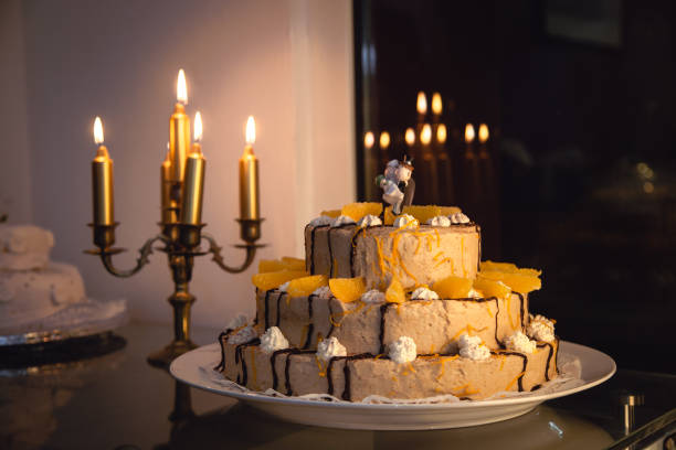 A stunning wedding cake adorned with orange slices and cream, complemented by flickering candles that create a romantic ambiance during the reception. The setting enhances the celebratory mood.
