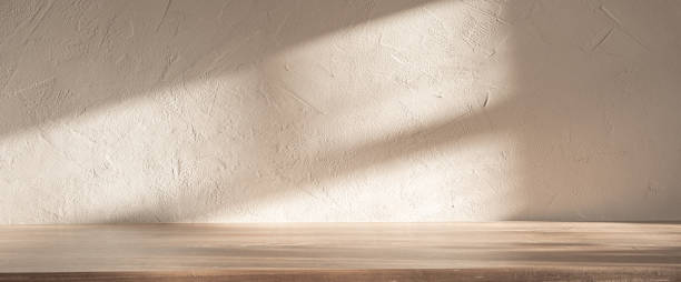 Soft light casting shadows on a textured wall and wooden surface in a serene indoor setting